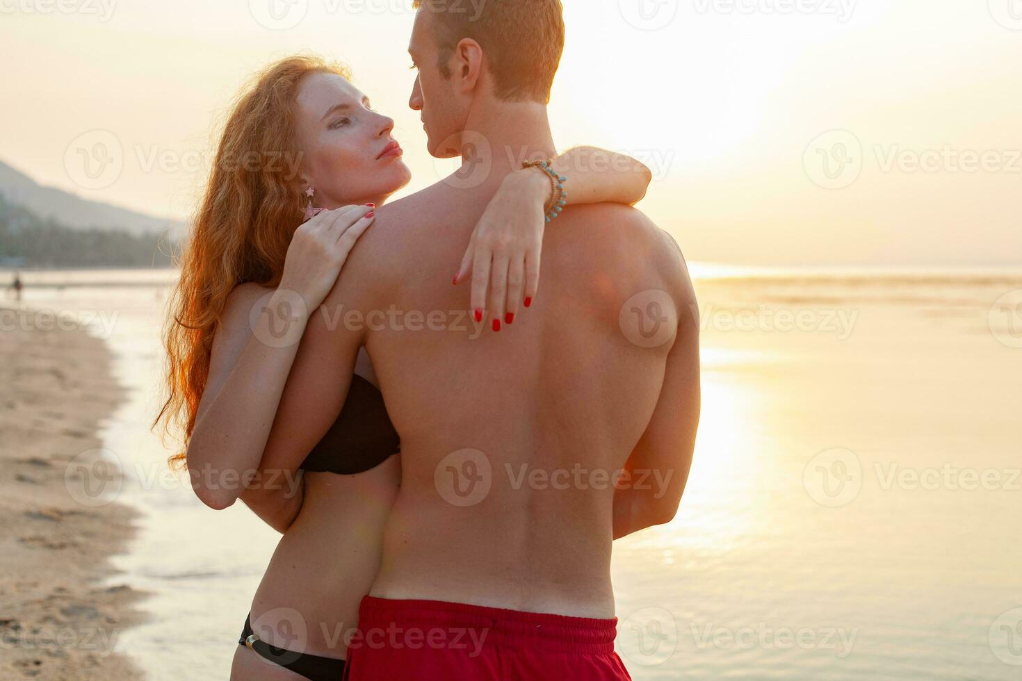 jovem sexy romântico casal dentro amor feliz em verão de praia juntos tendo Diversão vestindo nadar ternos foto