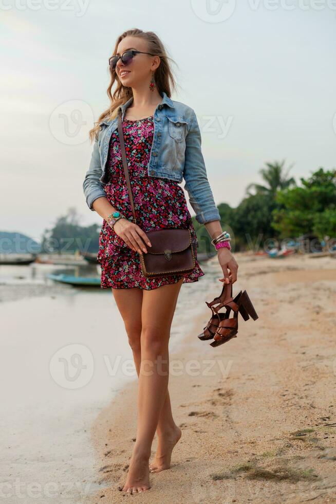 à moda mulher dentro verão vestir período de férias caminhando em de praia com sapatos dentro mão foto