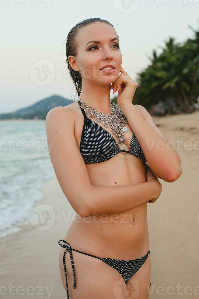 jovem lindo loiro mulher banhos de sol em areia de praia dentro bikini natação terno, vintage colar foto