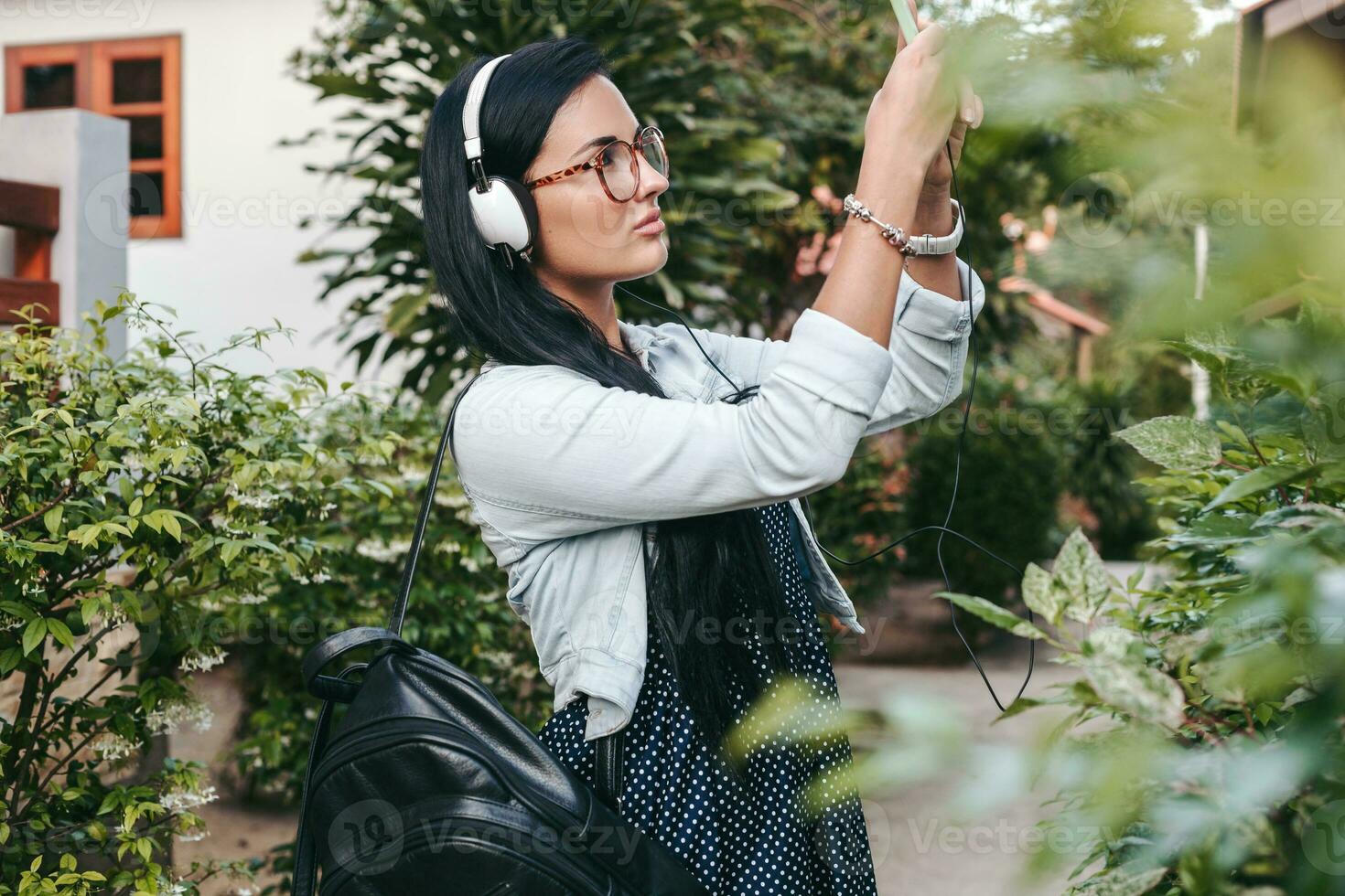 jovem à moda mulher caminhando com Smartphone, ouvindo para música em fones de ouvido foto