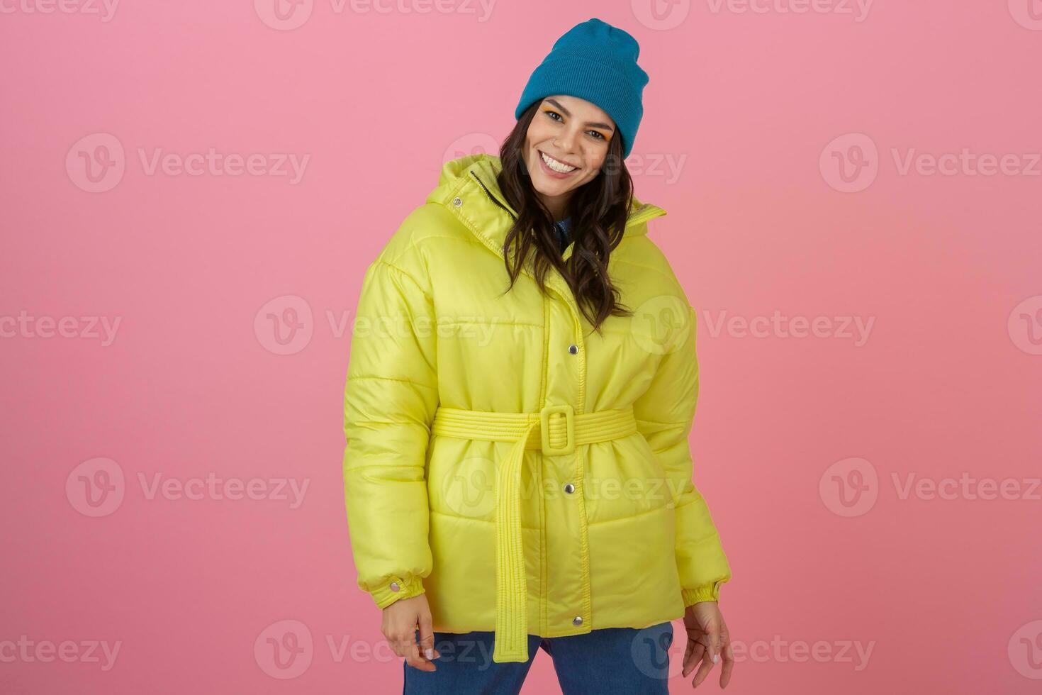 atraente ativo mulher posando em Rosa fundo dentro colorida inverno baixa Jaqueta do brilhante amarelo cor, sorridente diversão, caloroso casaco moda tendência, louco chocado surpreso face expressão foto