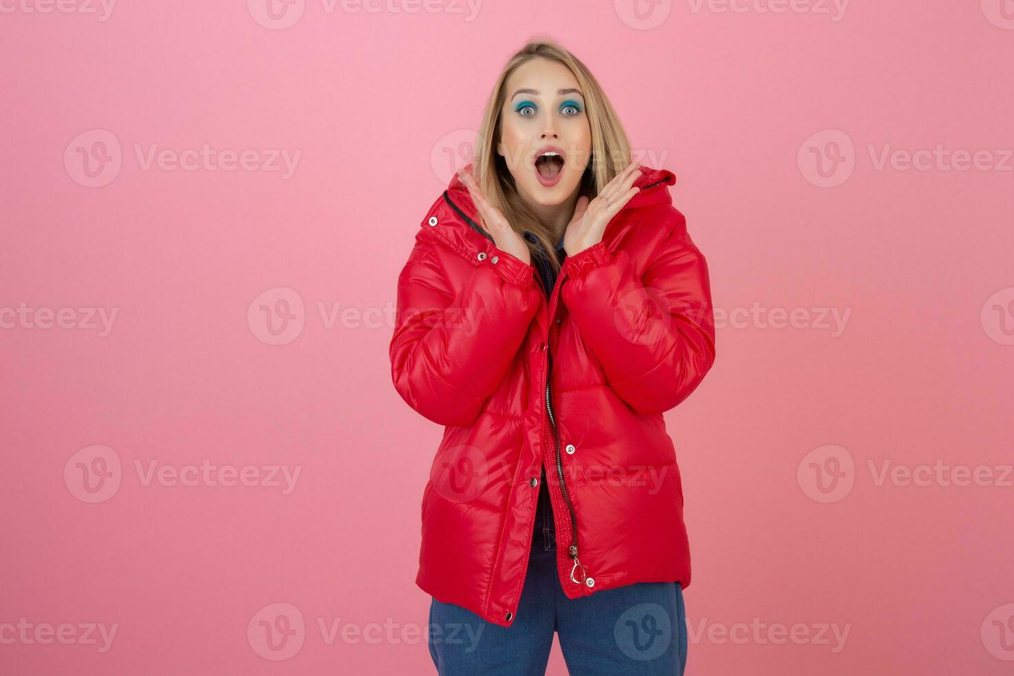 loiro feliz atraente ativo mulher posando em Rosa fundo dentro colorida inverno baixa Jaqueta do vermelho cor, tendo diversão, caloroso casaco moda tendência, sorridente foto