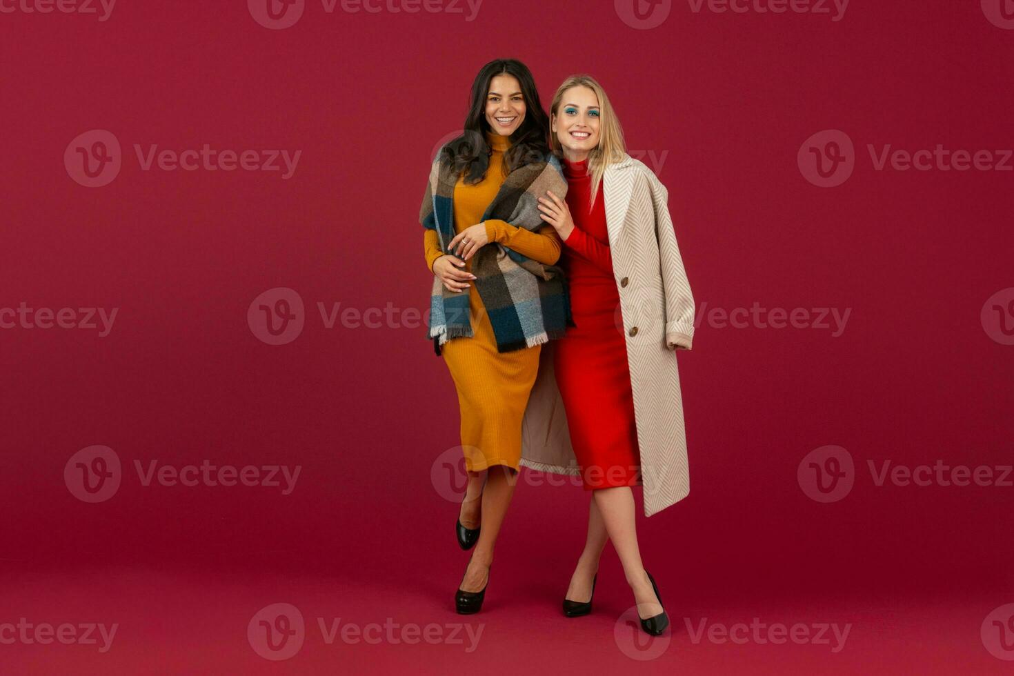 dois à moda mulheres dentro outono inverno moda vestir e casaco posando isolado cheio altura em vermelho estúdio fundo foto