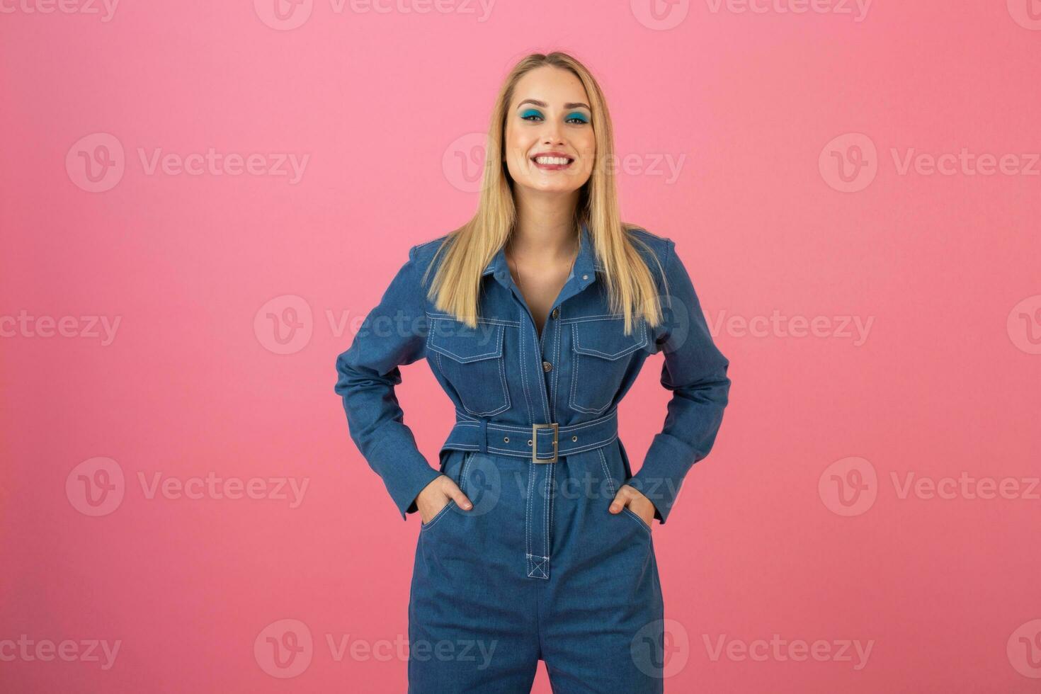 animado atraente menina posando em Rosa fundo dentro jeans No geral moda tendência foto