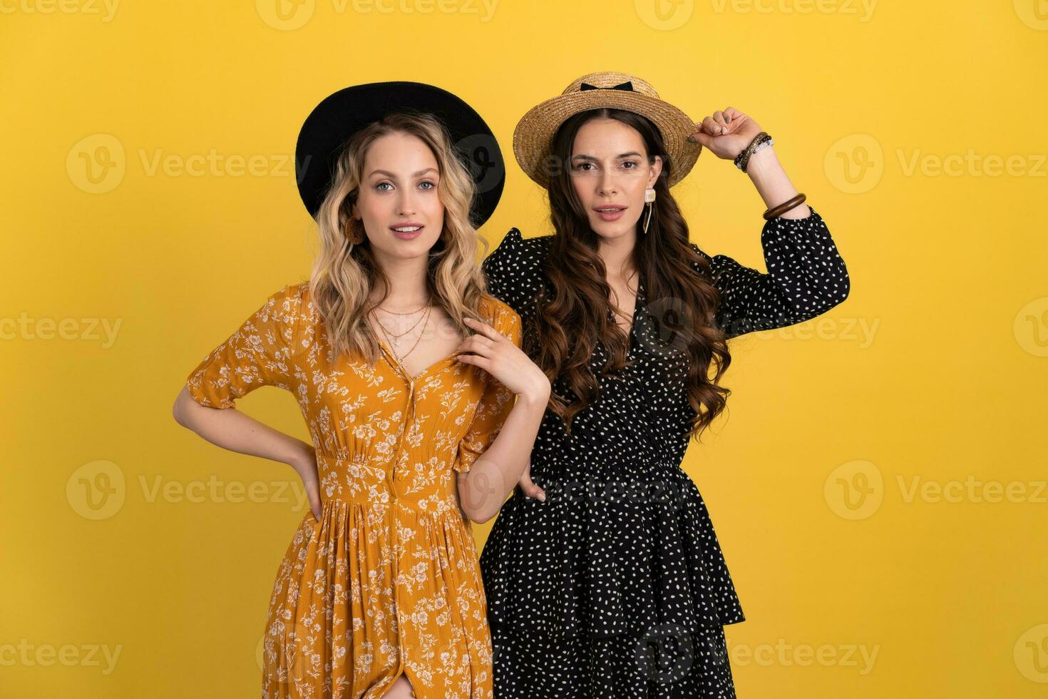 lindo mulheres amigos juntos isolado em amarelo fundo dentro Preto e amarelo vestir e chapéu foto