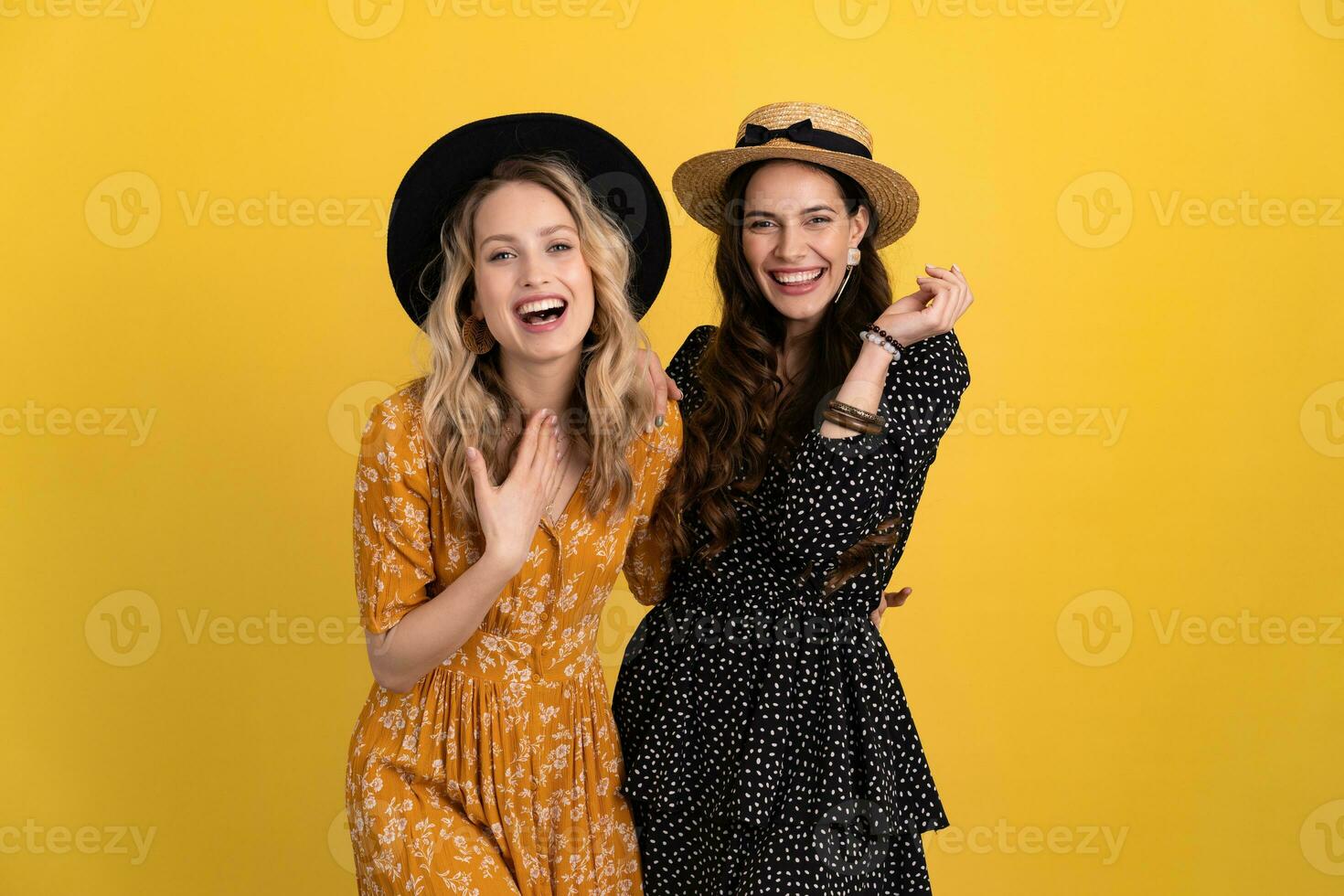 lindo mulheres amigos juntos isolado em amarelo fundo dentro Preto e amarelo vestir e chapéu foto