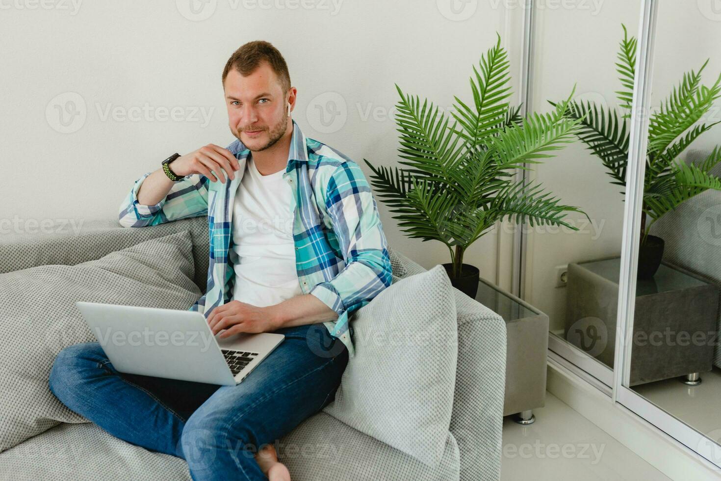 bonito ocupado focado homem dentro camisa sentado relaxado em sofá às casa às mesa trabalhando conectados foto
