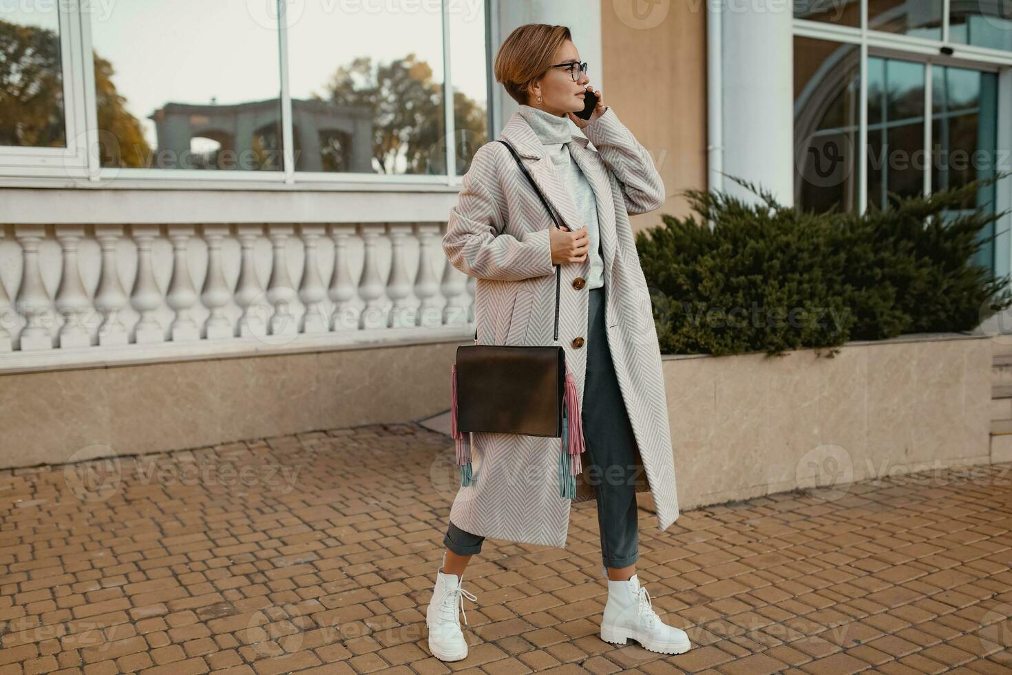 à moda elegante mulher caminhando dentro rua dentro elegante estilo casaco foto