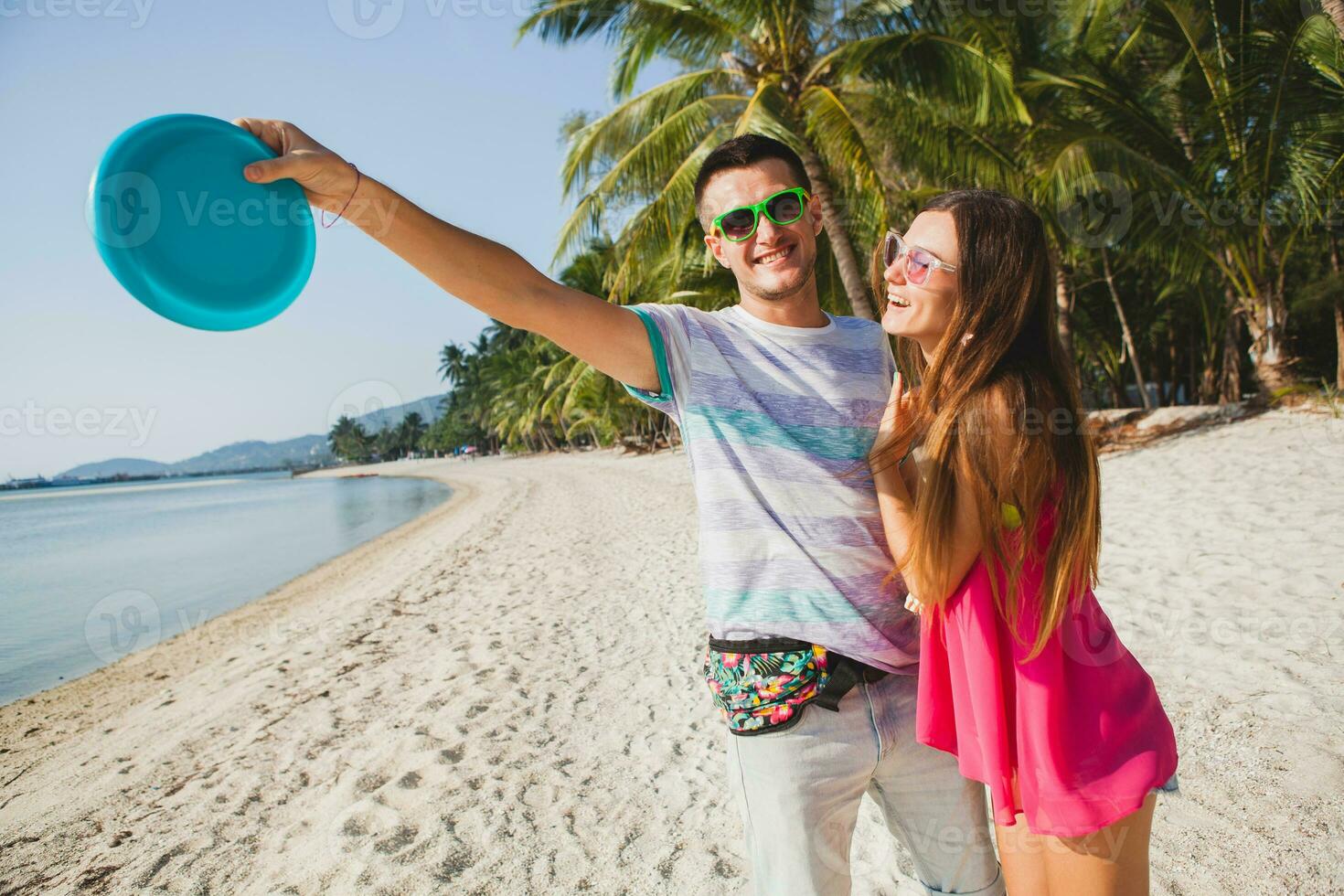 jovem casal homem e mulher jogando vôo disco em tropical praia, verão período de férias foto