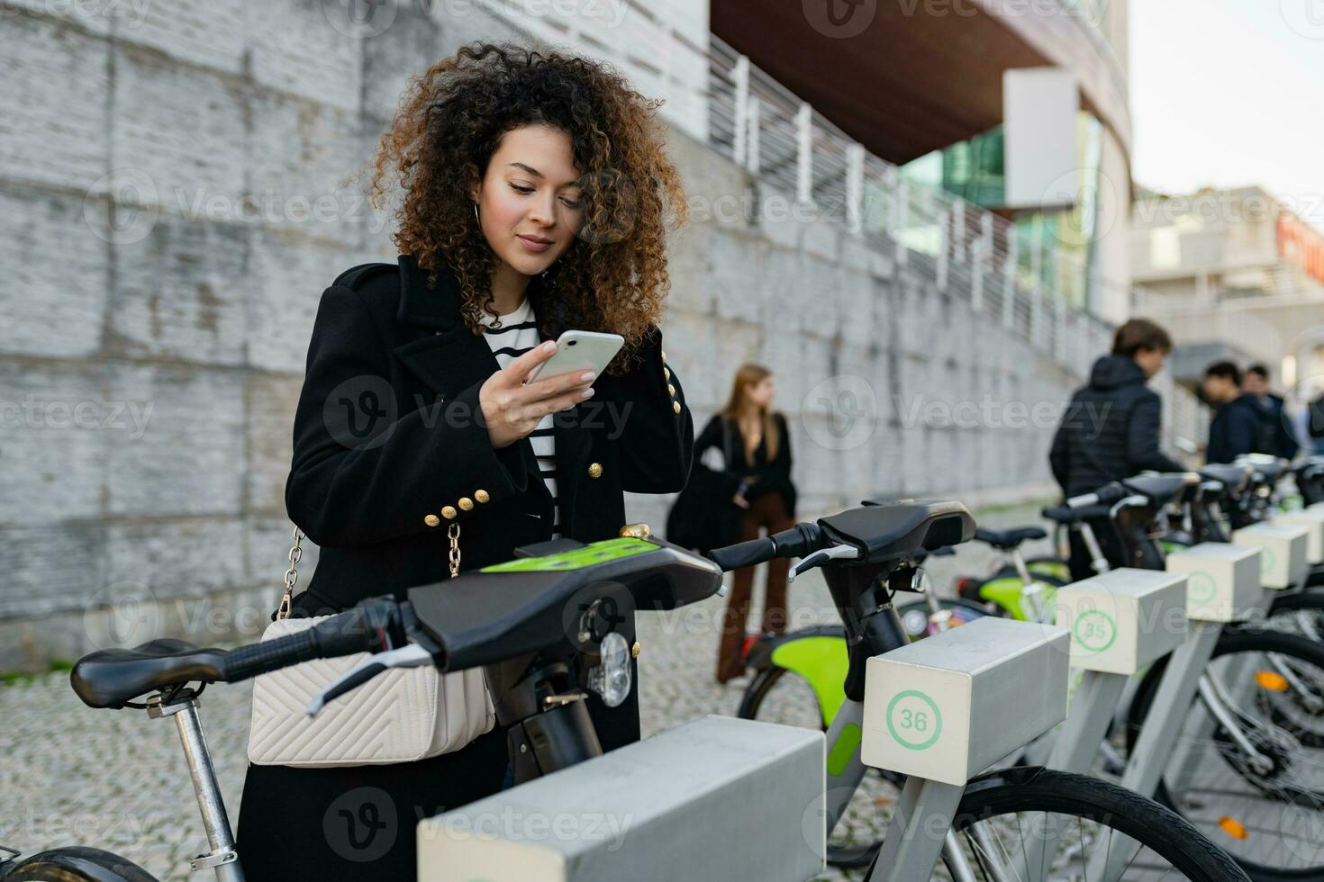 bonita encaracolado mulher alugando uma bicicleta dentro rua com a aplicativo foto