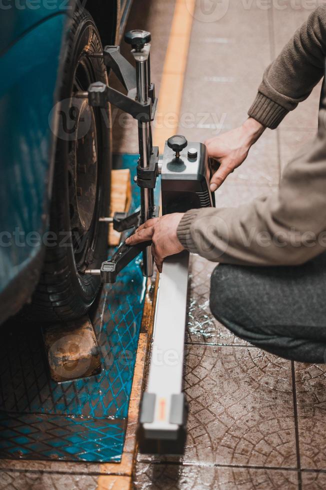 close-up de um pneu preso por uma niveladora que passa o alinhamento automático das rodas na garagem, garagem e ferramentas para o mecânico. foto