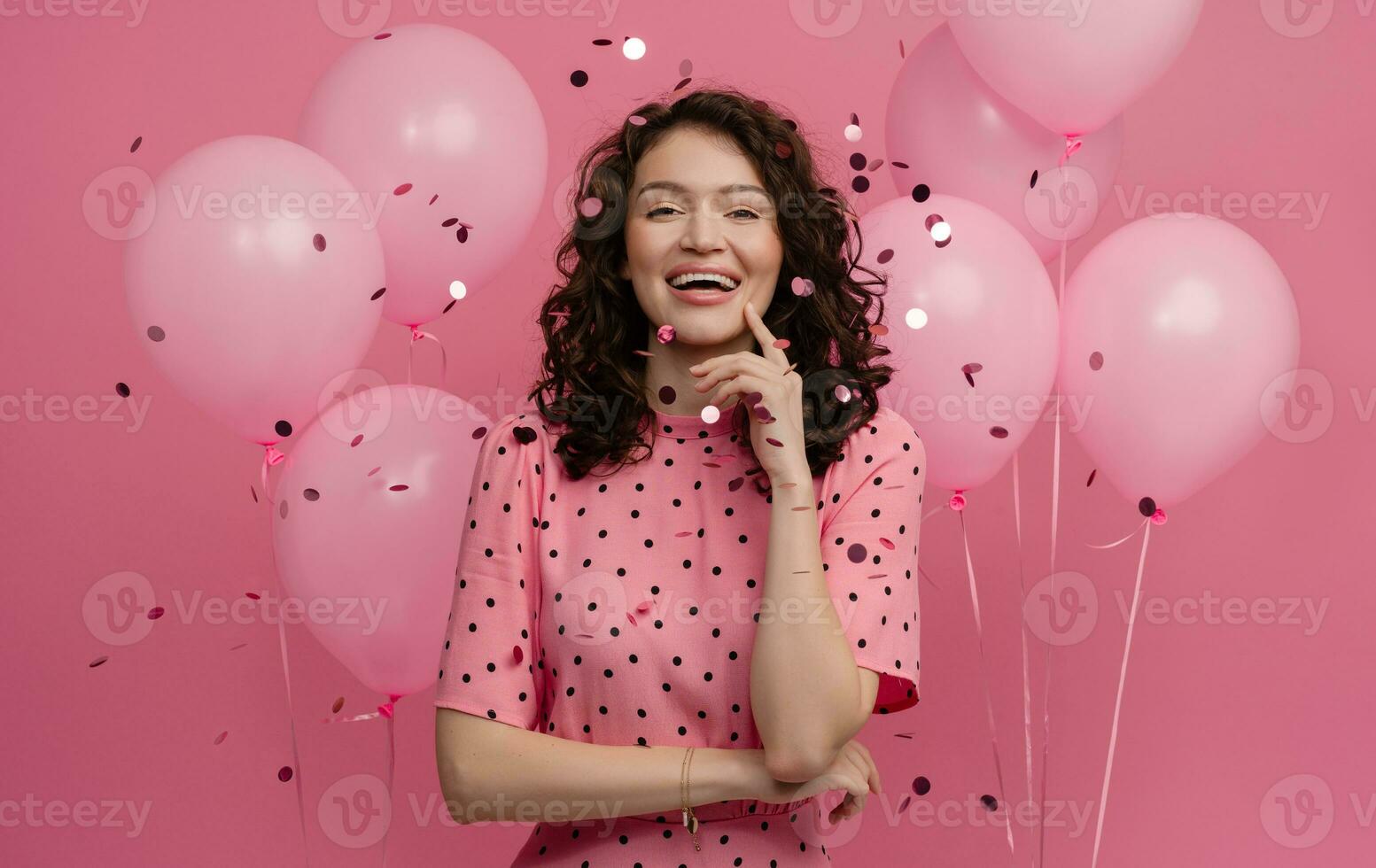 bonita jovem mulher posando isolado em Rosa estúdio fundo com Rosa ar balões e confete foto