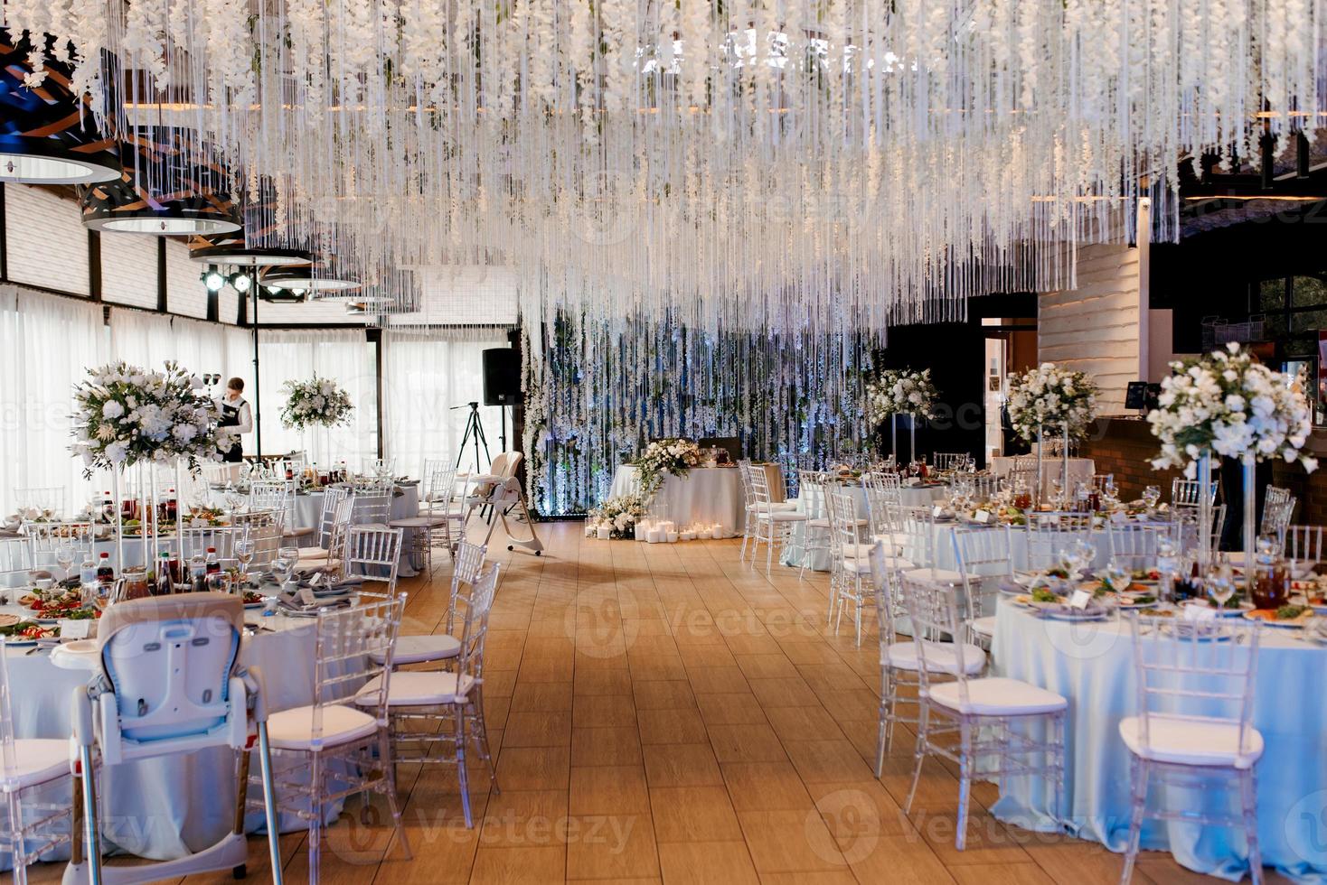 o presidium dos noivos no salão de banquetes do restaurante é decorado com velas e plantas verdes foto