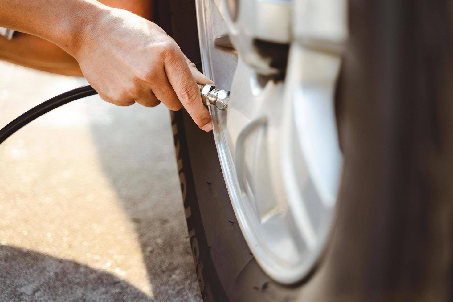 close-up de homem asiático inflando o pneu no posto de gasolina. foto