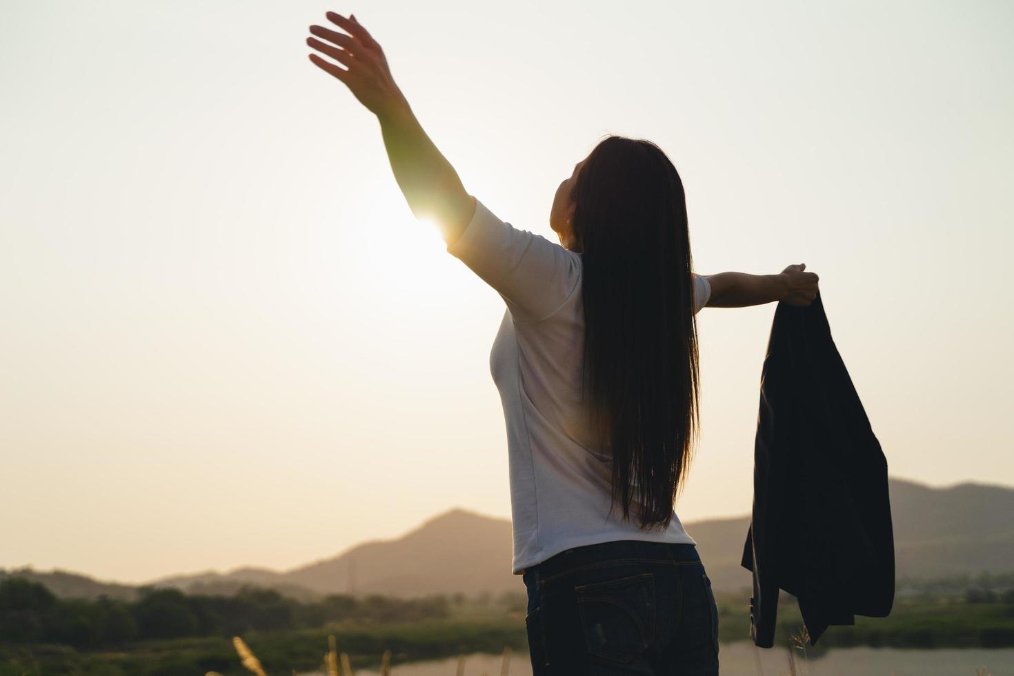 mulher de negócios feliz abrindo os braços e observando a silhueta da montanha. conceito de sucesso empresarial, emoções de liberdade foto