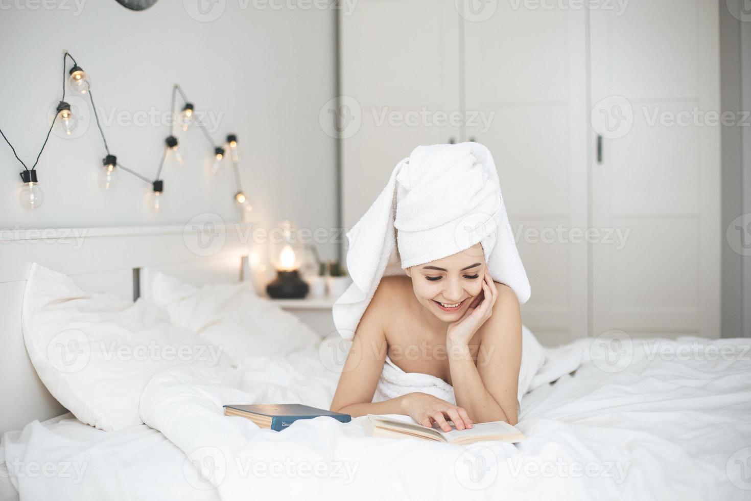 jovem mulher feliz lendo livro de papel na cama. foto