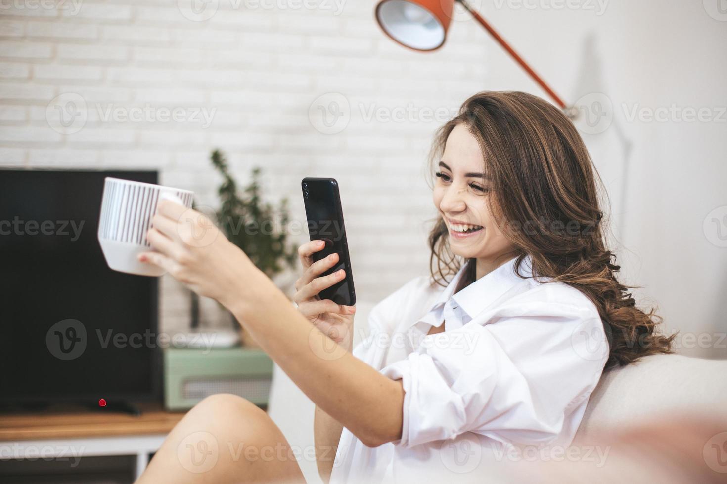 jovem faz selfie sentado no sofá em casa. foto