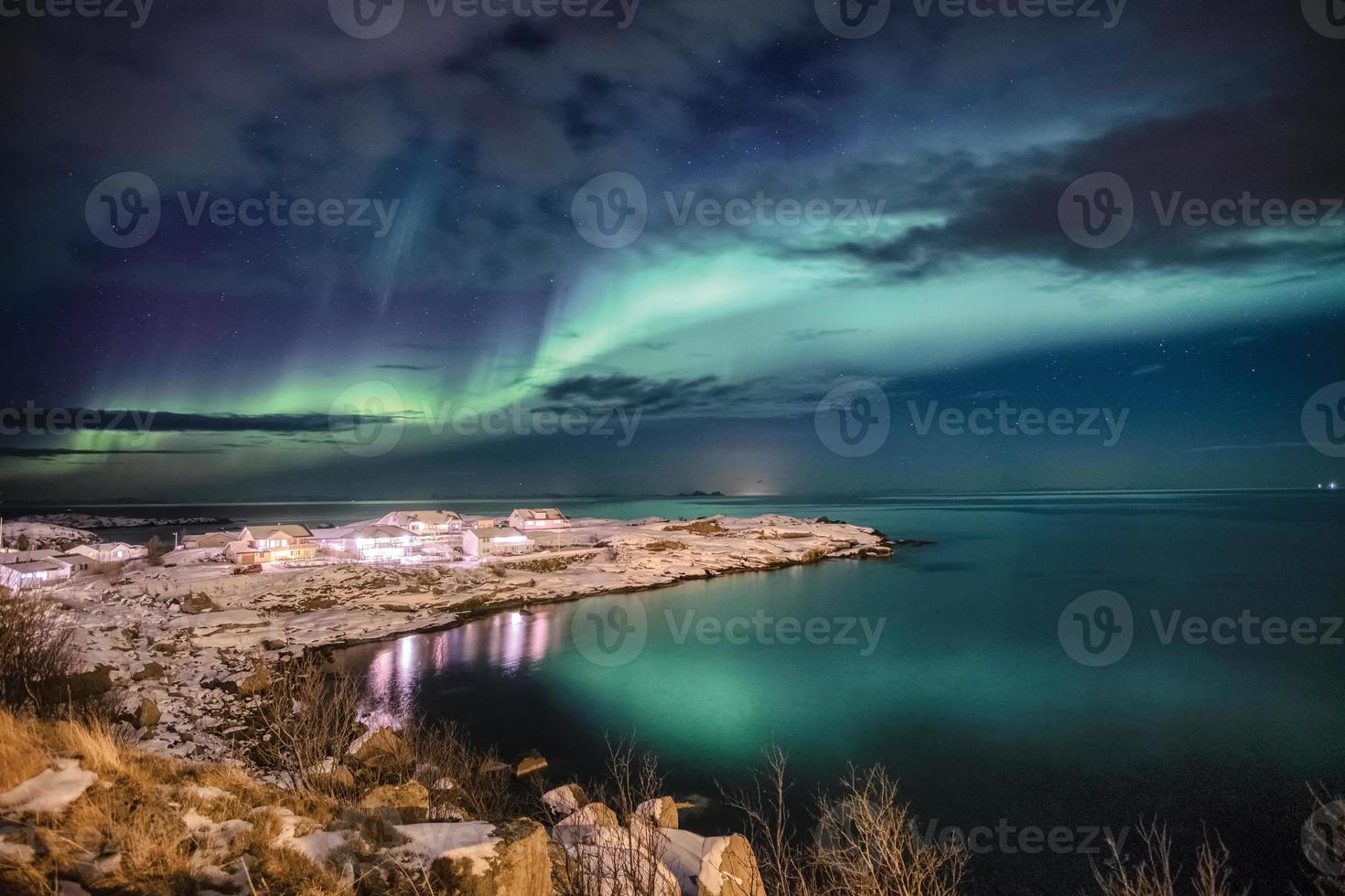 iluminação de aldeia escandinava com aurora boreal no cabo de neve foto