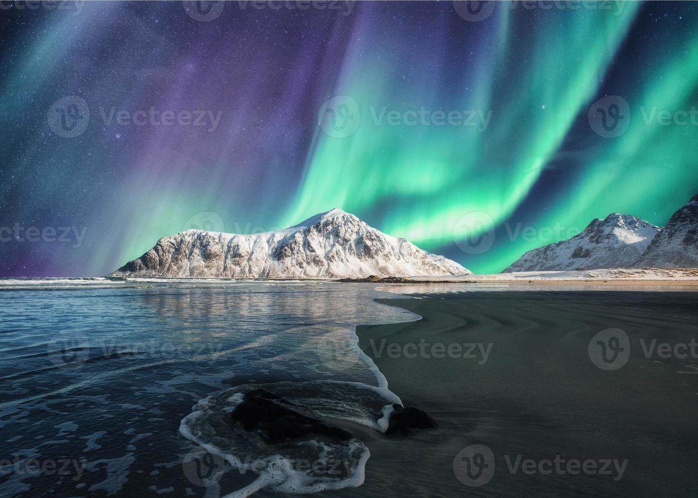 aurora boreal, aurora boreal acima na montanha nevada na praia skagsanden nas ilhas lofoten foto