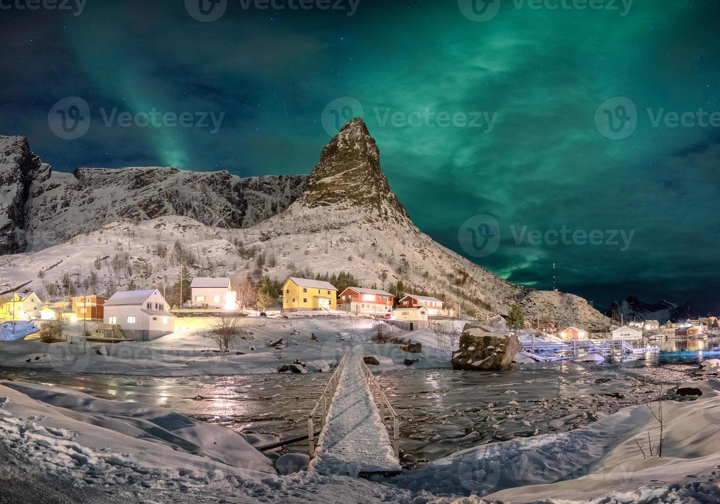 vila escandinava com aurora boreal sobre montanha nevada foto