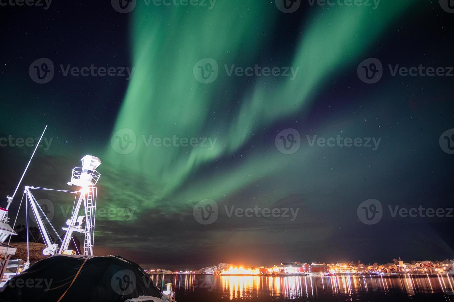 aurora boreal, aurora boreal sobre a cidade iluminada de Reine, na costa das ilhas Lofoten foto