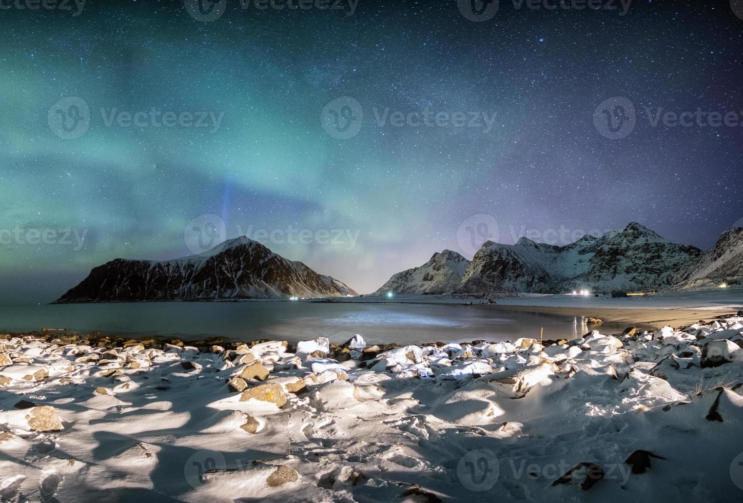panorama da aurora boreal com estrelas ao longo da cordilheira com litoral nevado foto