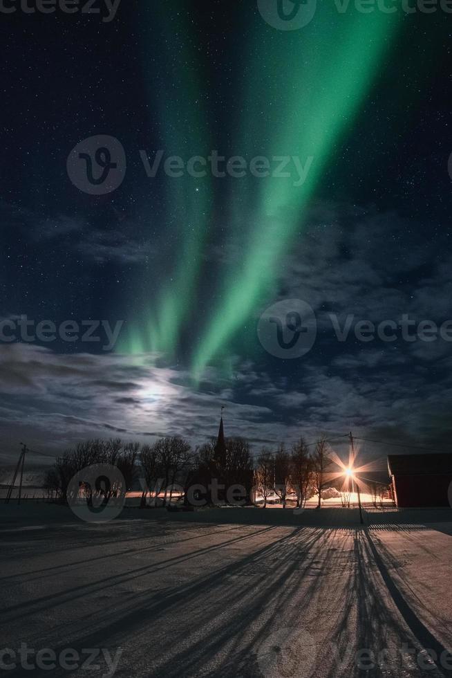 aurora boreal com estrelas no céu noturno sobre a igreja de flakstad nas ilhas lofoten foto