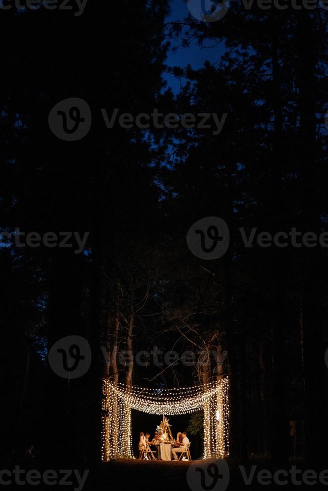 área para banquetes de casamento em uma floresta de pinheiros com um arco ao fundo para várias pessoas foto