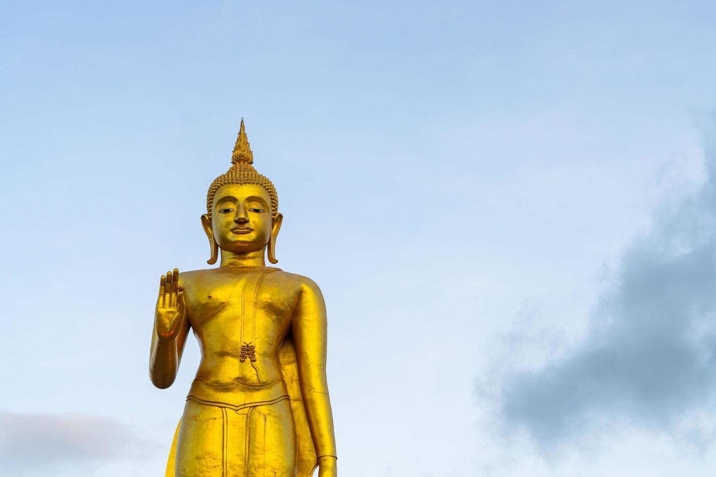 uma estátua de Buda dourado com céu no topo da montanha no parque público do município de hat yai, província de Songkhla, Tailândia foto