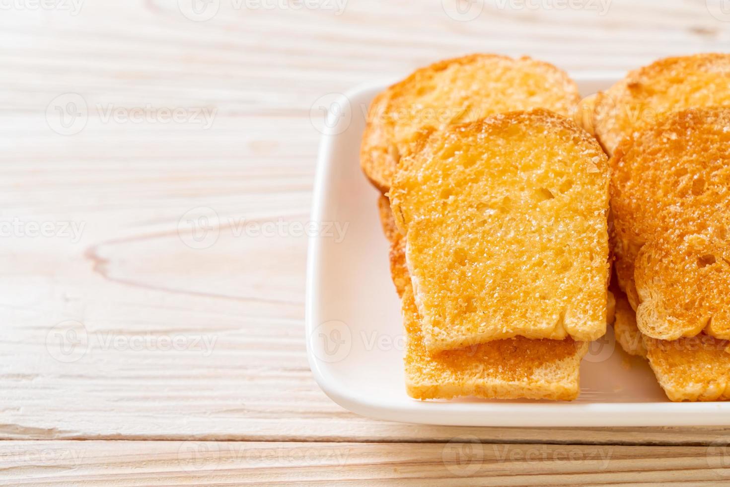 pão crocante assado com manteiga e açúcar no prato foto