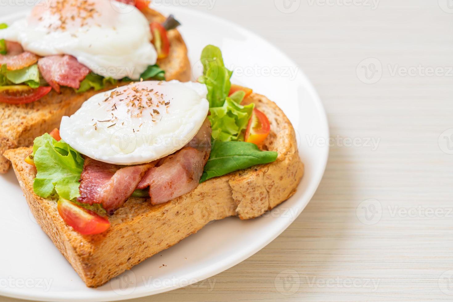 pão integral torrado com vegetais, bacon e ovo ou ovo benedict, no café da manhã foto