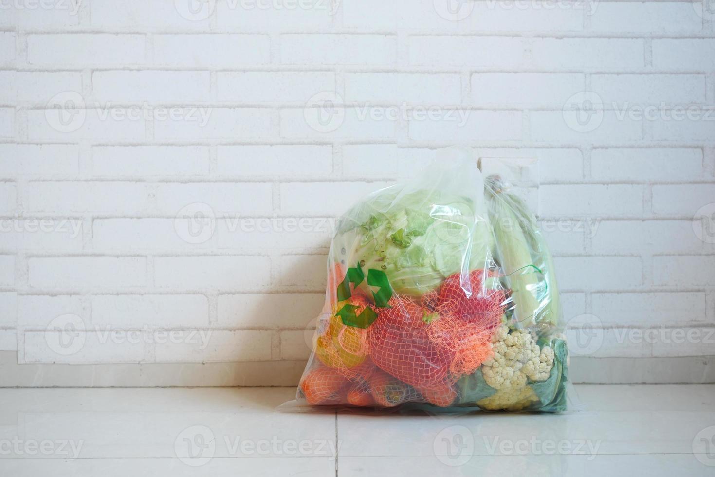 setas recicladas assinam em uma sacola de compras com vegetais no chão foto