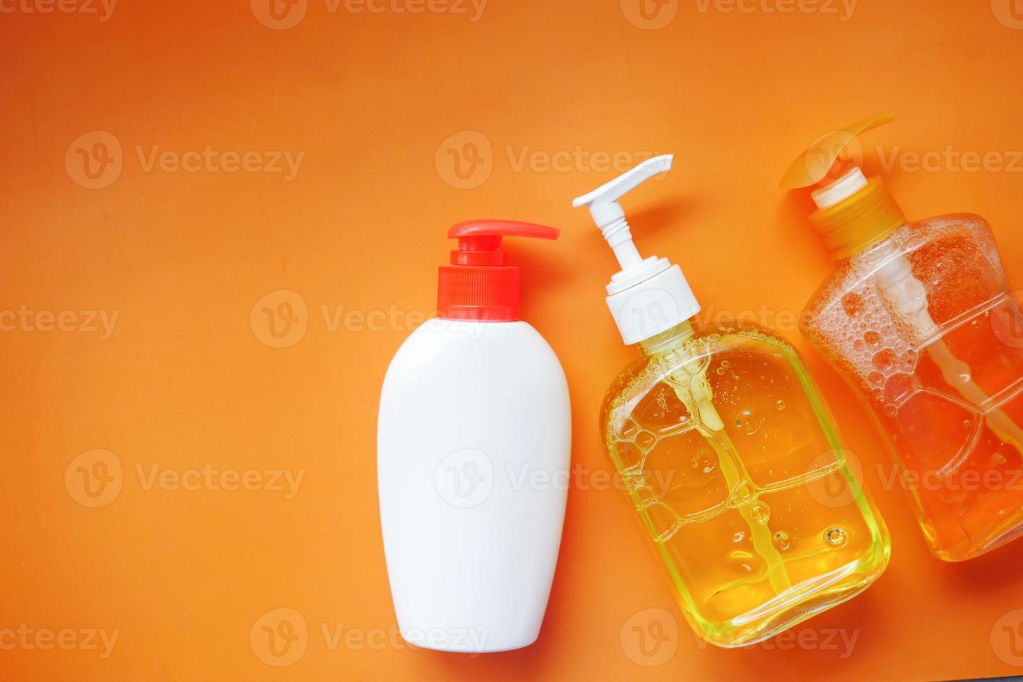 líquido para lavagem de mãos em um recipiente em fundo laranja foto