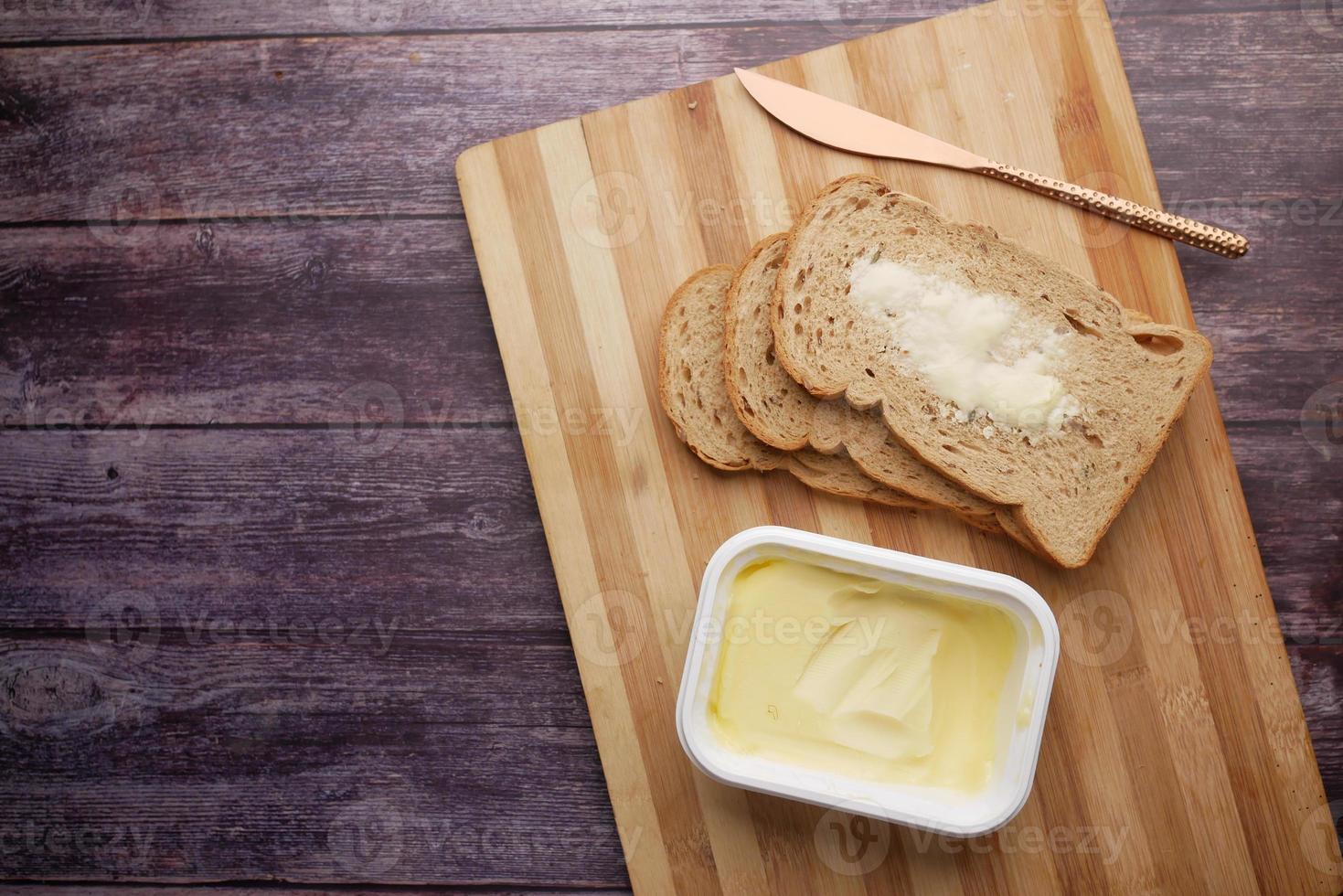 fatia de manteiga e pão integral na tábua de cortar foto