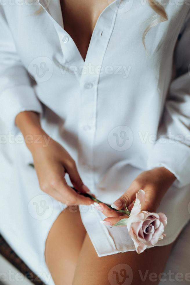 garota em uma camisa branca segurando uma rosa nas mãos foto