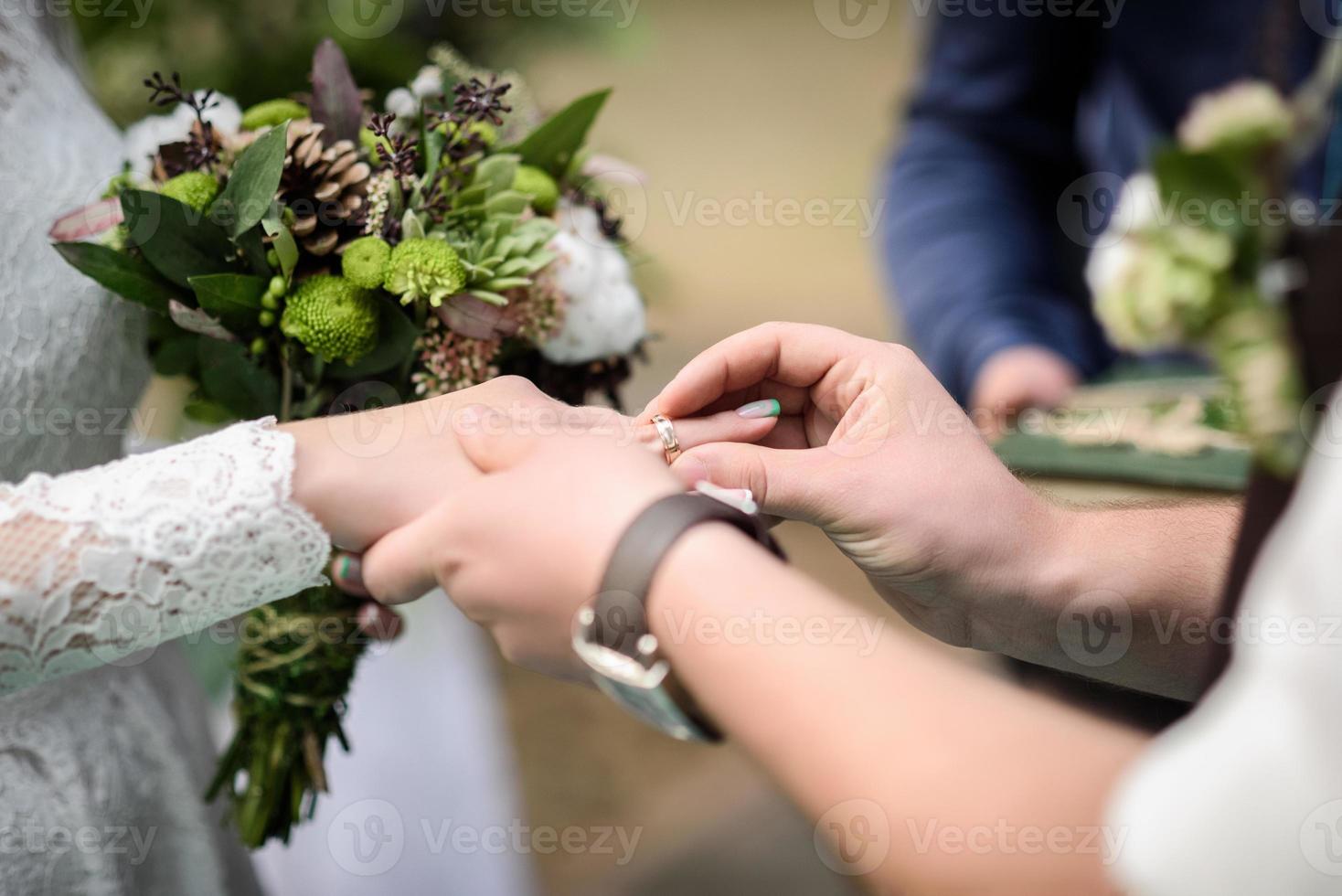 noivo coloca aliança de casamento foto