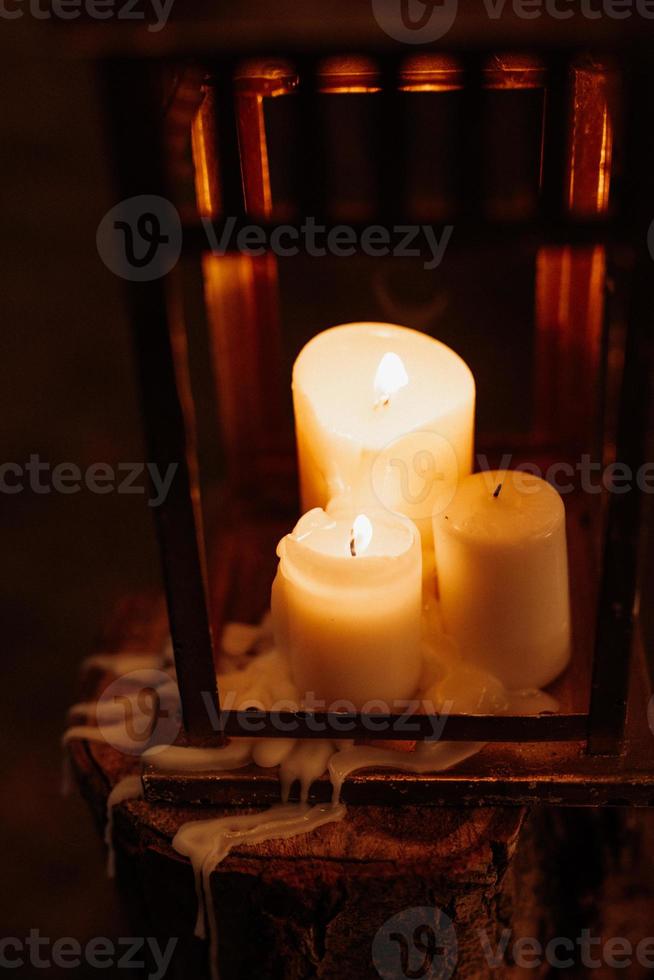 queimando velas em uma noite escura em uma lanterna de madeira foto