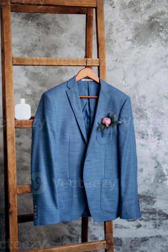 terno clássico blazer azul pendurado em uma escada de madeira foto