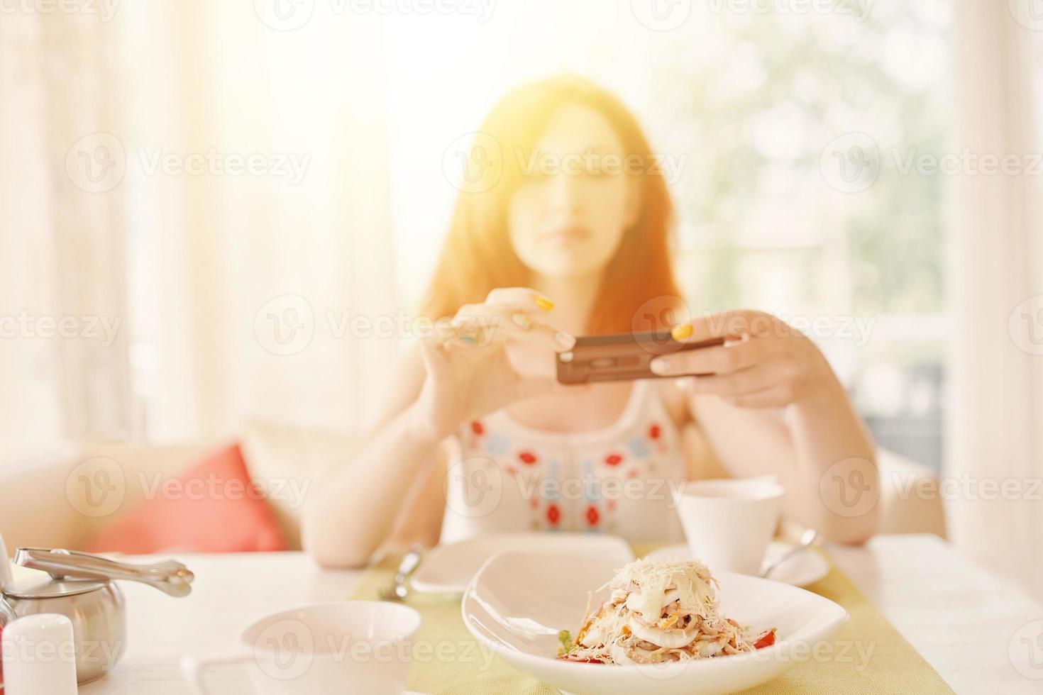 mulher ruiva tira fotos de salada na câmera do smartphone.
