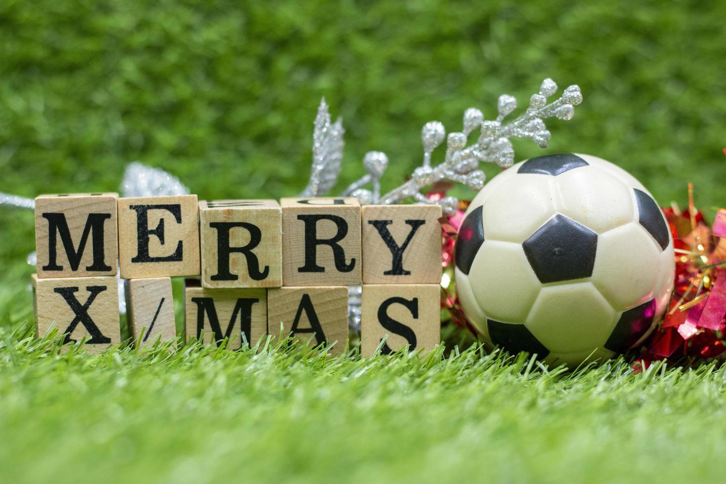 a bola de futebol com o bloco de madeira do feliz natal está na grama verde foto