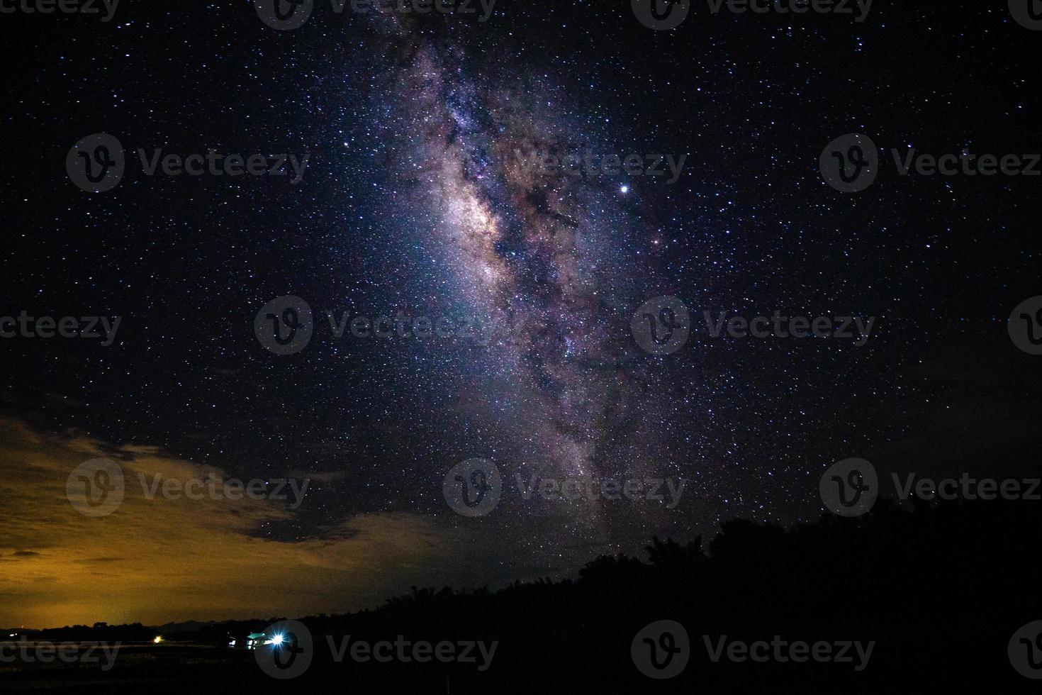 paisagem noturna com a Via Láctea e a luz de casa nas montanhas da Tailândia foto