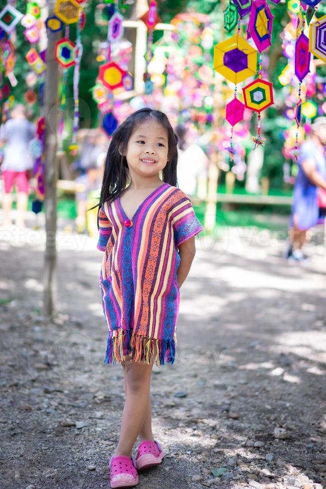 retrato de uma menina asiática feliz em um vestido com bandeiras tung em pé no parque foto