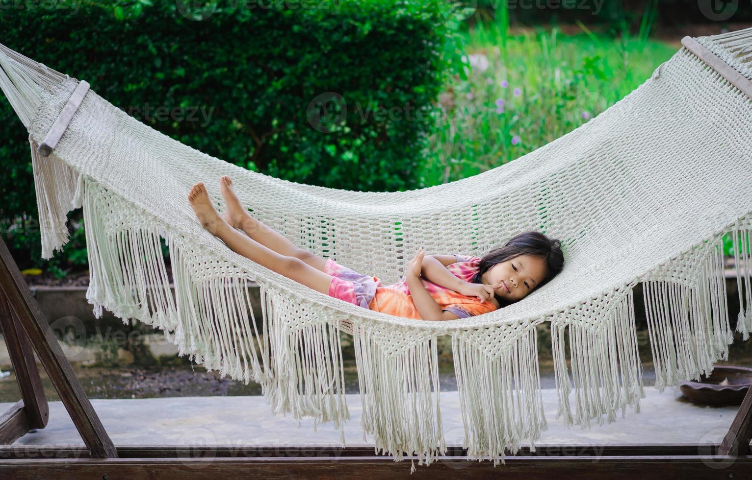 menina asiática com vestido deitada no berço foto