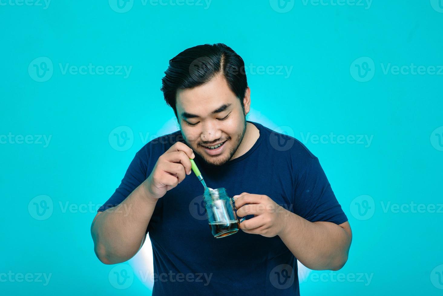 o jovem mexeu uma xícara de café com um grande sorriso. fundo azul foto