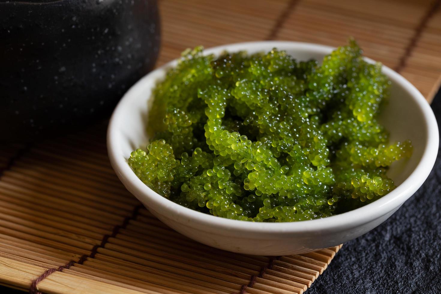 algas ovais de uvas do mar, close-up caviar verde sobre fundo escuro foto