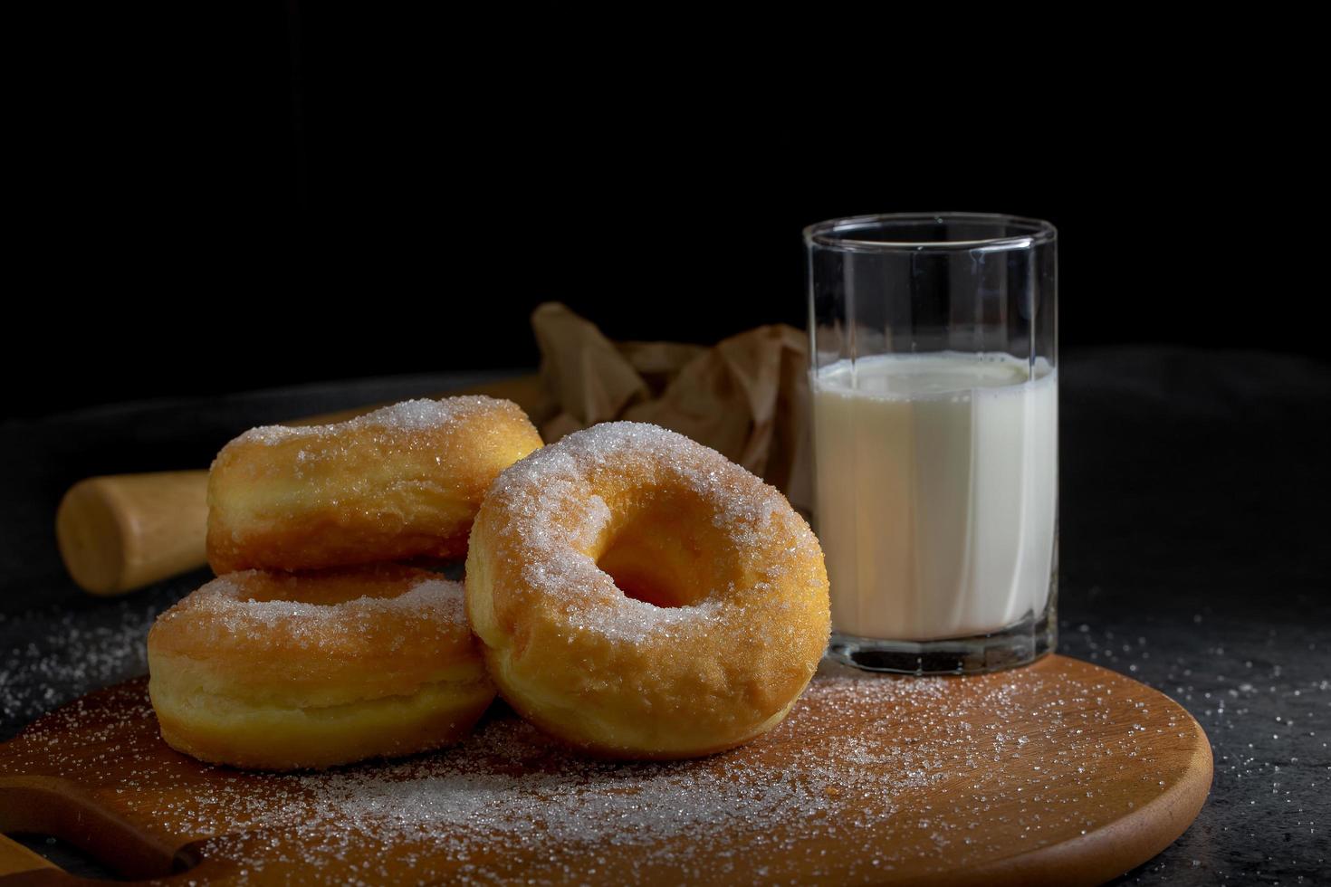 donuts com açúcar em uma placa de madeira sobre um fundo escuro de mesa. foto