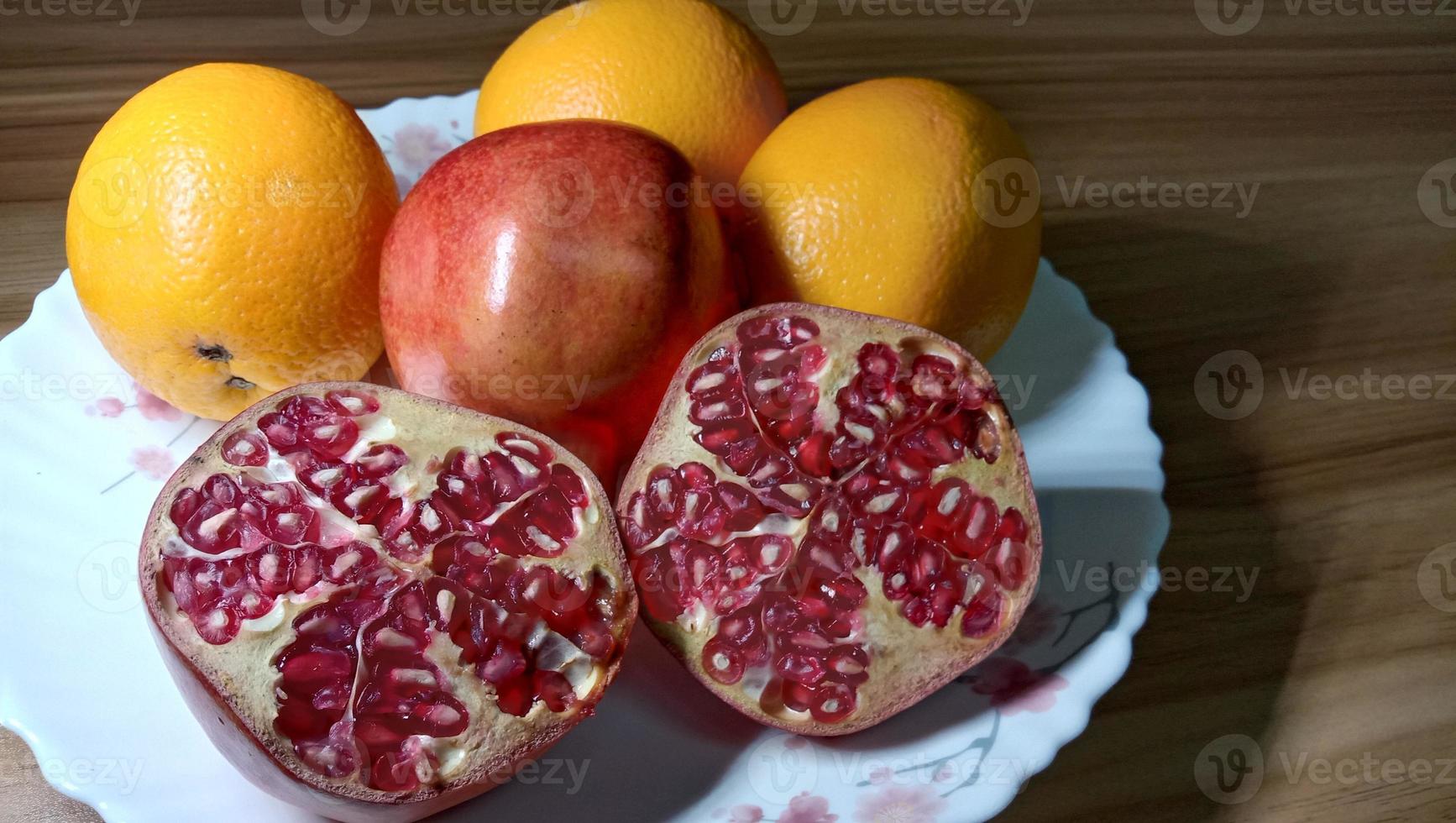 Close up de romã e laranja no prato foto