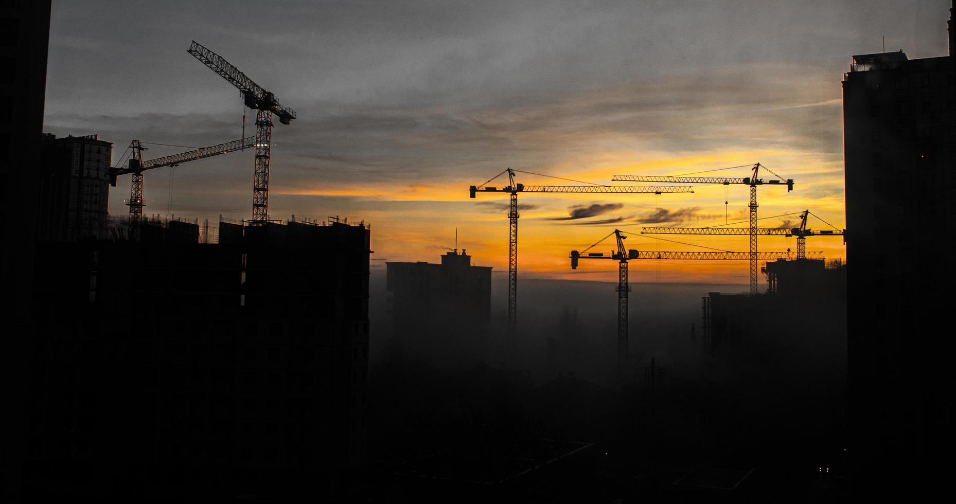 construção de edifícios com guindastes durante o pôr do sol foto