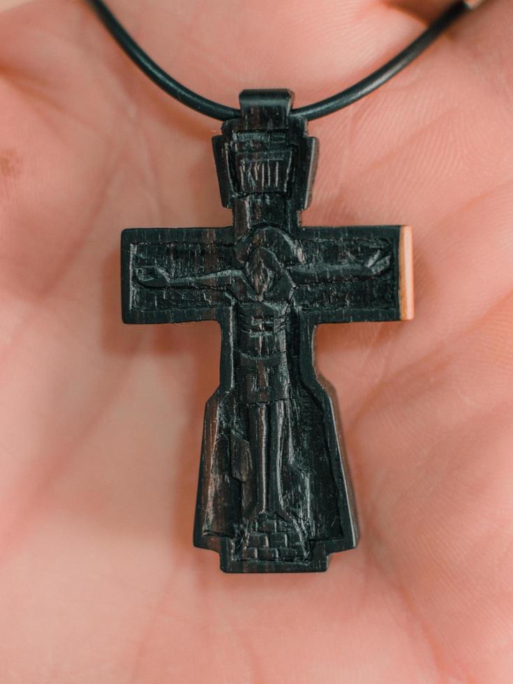 fechar-se. cruz ortodoxa de madeira na palma da mão de um homem foto