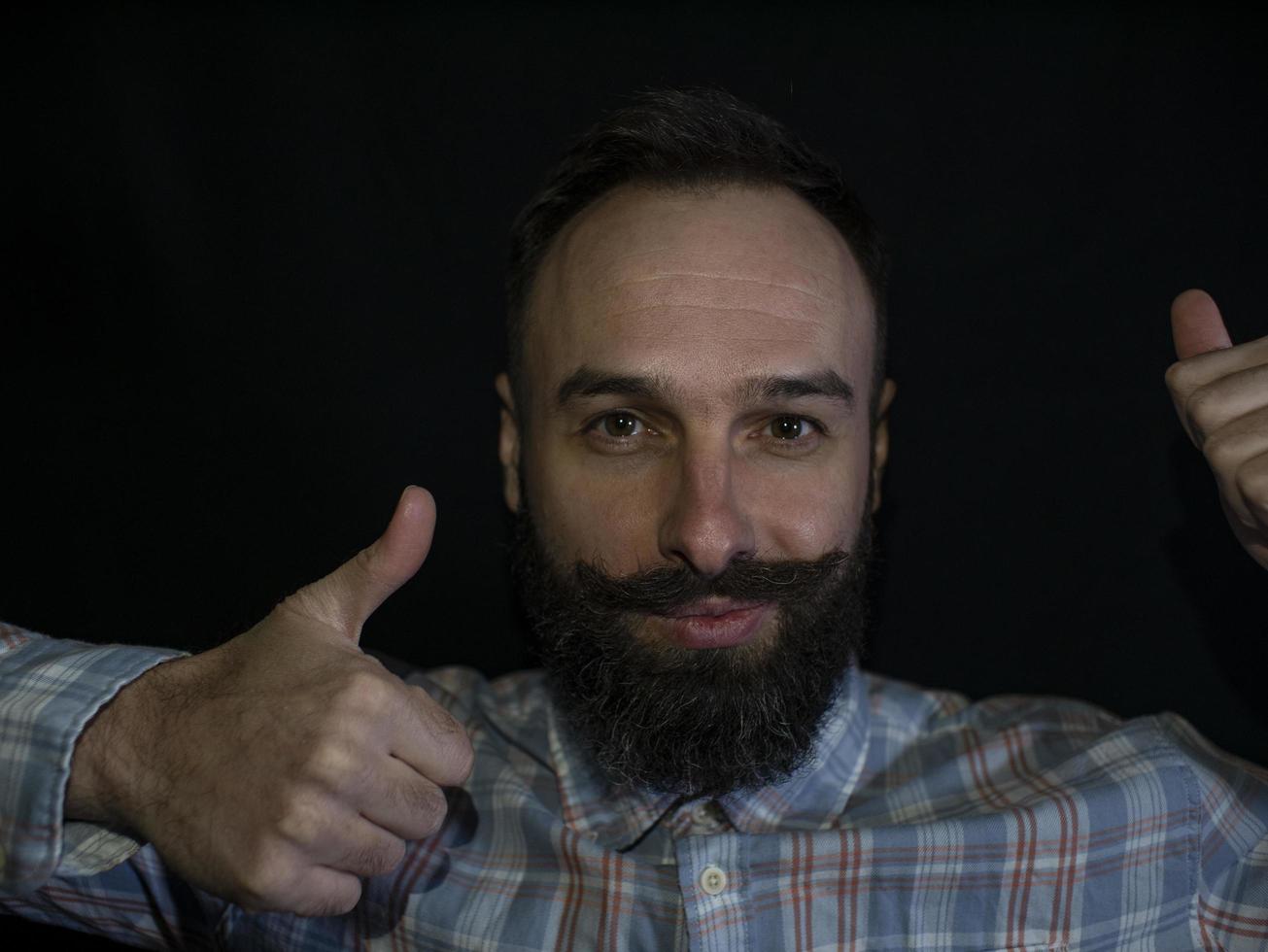 homem com barba e bigode fazendo cara no fundo preto foto